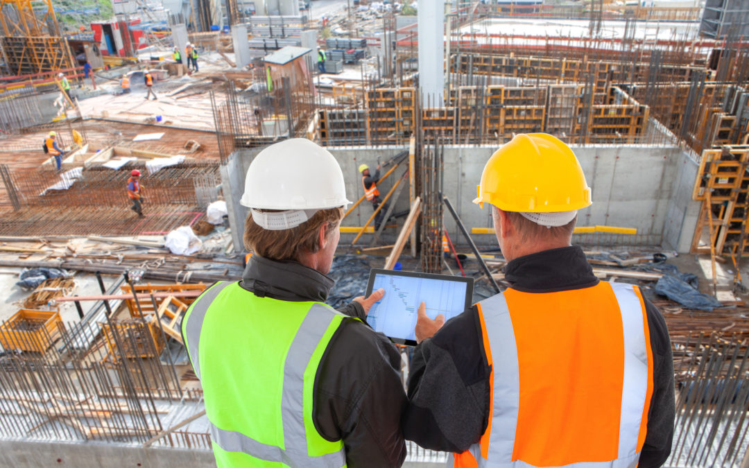 Two construction managers overlooking a large-scale commercial construction project